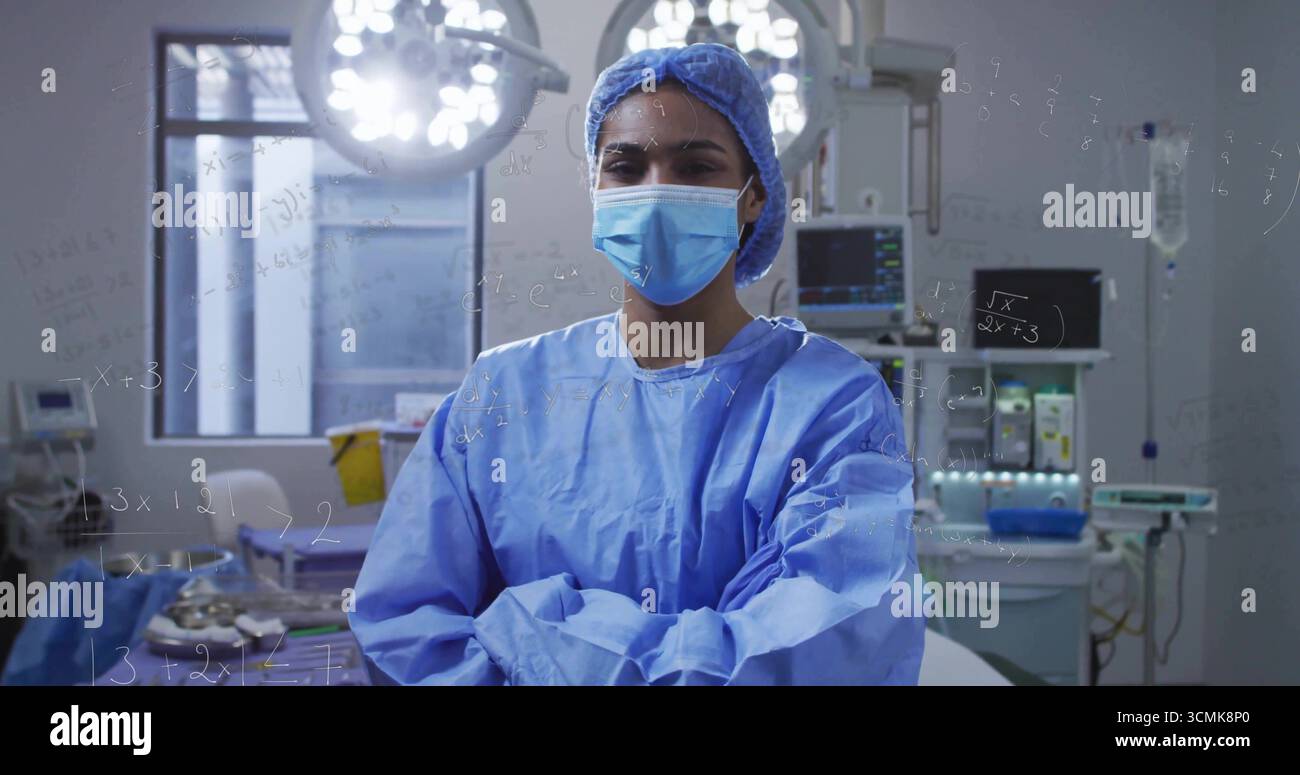 Chirurgien debout croisant les bras sous les lumières chirurgicales dans le BLOC OPÉRATOIRE, avec machine d'anesthésie et statif IV Banque D'Images