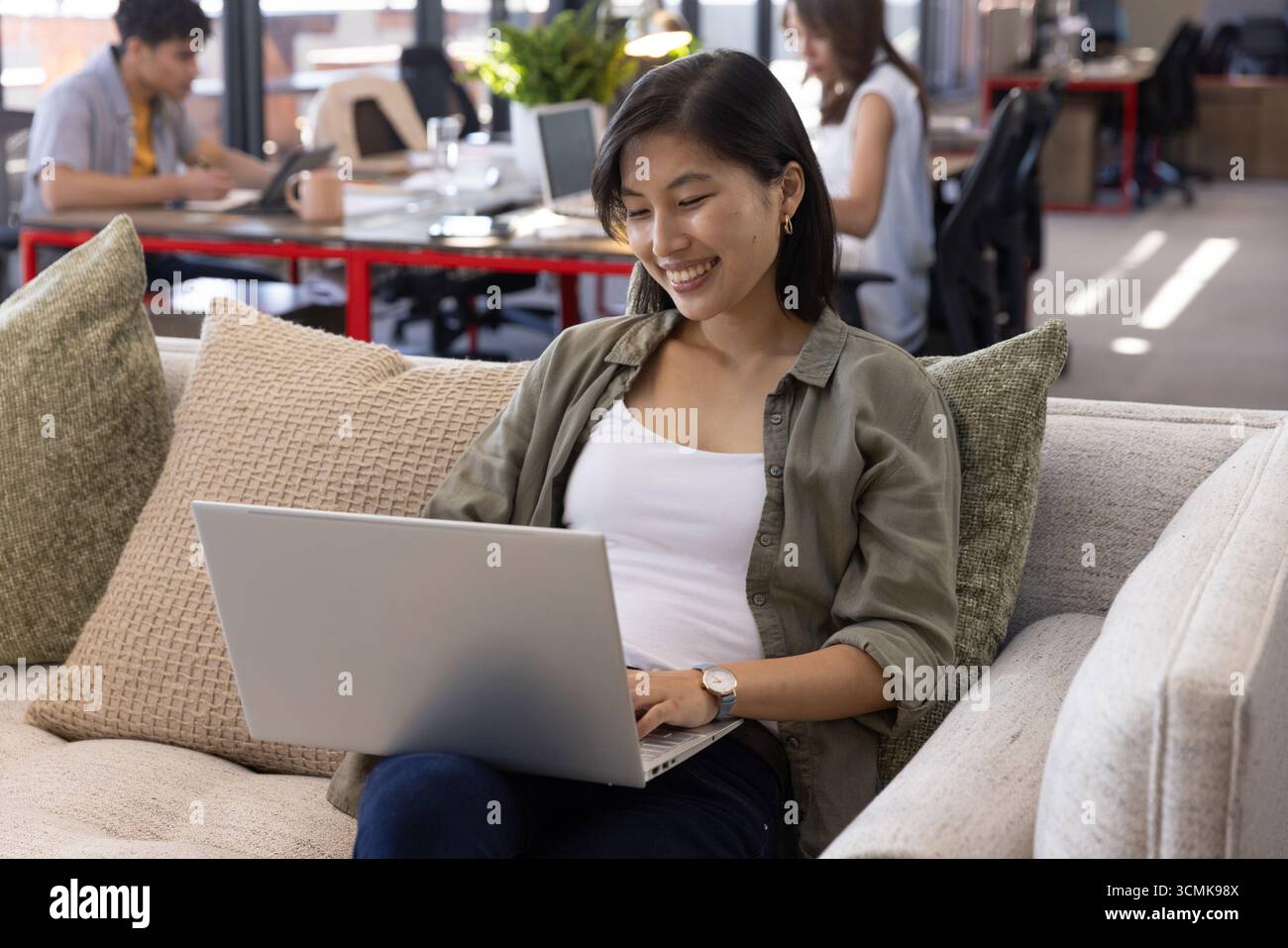 Divers collègues travaillant dans le salon de bureau moderne sur le canapé et au bureau avec tasse à café Banque D'Images