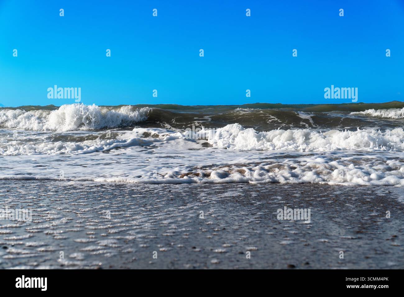 Mer bleue et grandes vagues et mousse. Tempête vague éclaboussant sur des galets en mer. Vagues de l'océan qui roulent. Fond de plage paradisiaque d'été. Puissantes vagues marines Banque D'Images