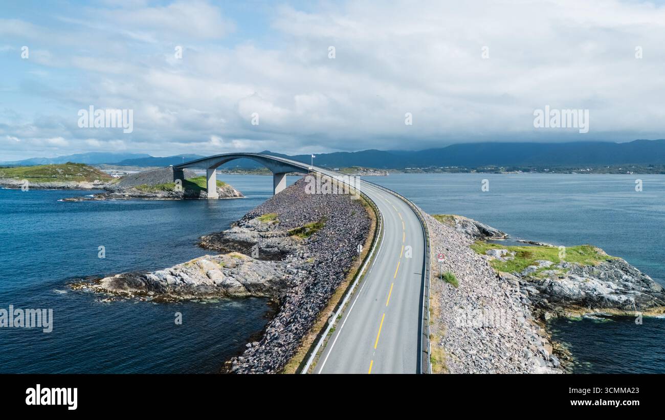 Des routes à couper le souffle sillonnent la côte rocheuse le long de la route de l'océan Atlantique en Norvège, mettant en valeur des paysages spectaculaires et des eaux sereines sous un ciel vibrant. Banque D'Images