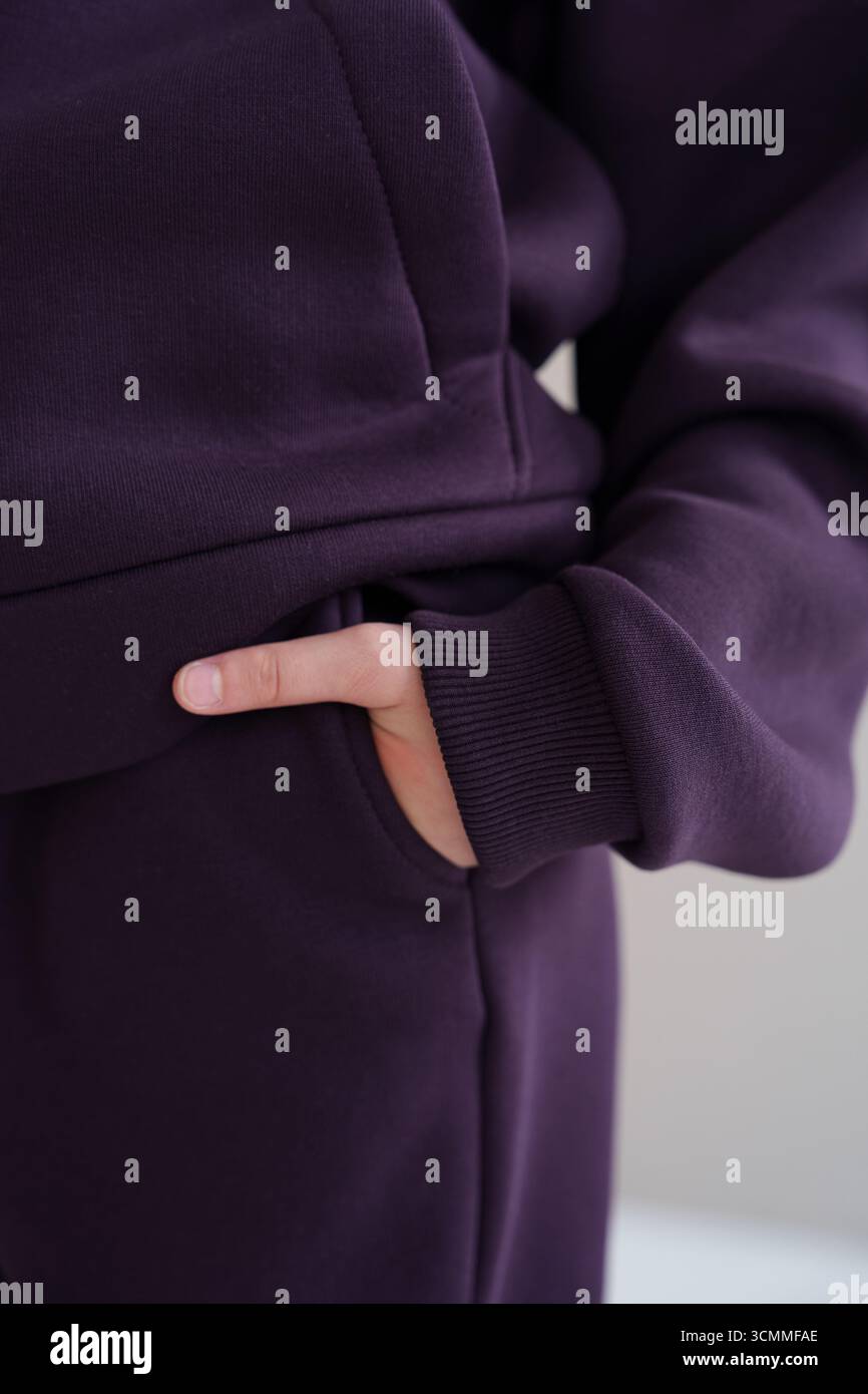 Gros plan d'un sweat à capuche violet avec l'accent sur la poche et le poignet. L'image transmet la texture du tissu, les détails de couture et une sensation de confort Banque D'Images