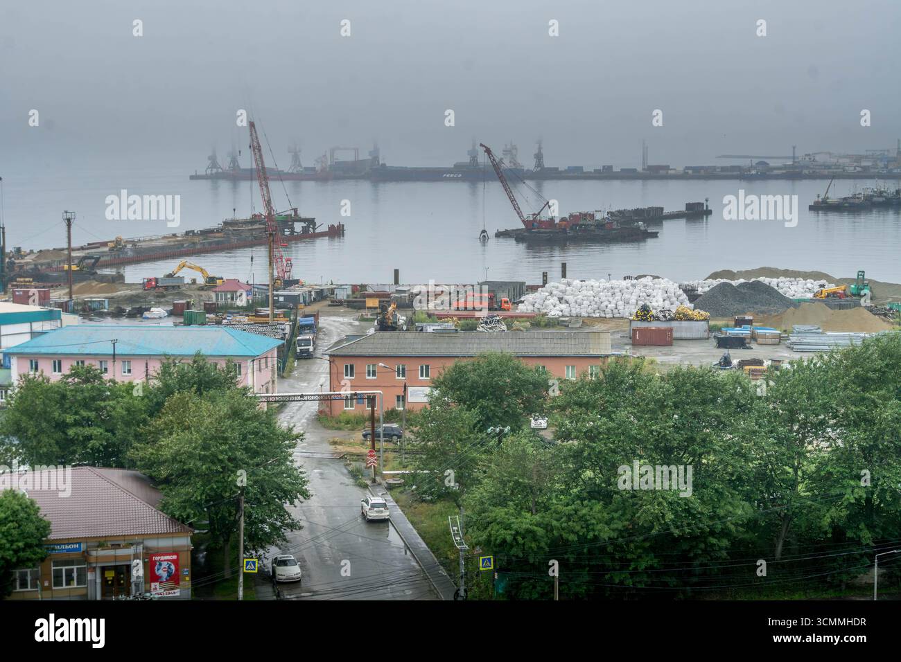 Panorama industriel du front de mer avec grues et navires, Korsakov, Sakhaline, Russie, avec entrepôts portuaires, matériaux de construction, rue humide Banque D'Images