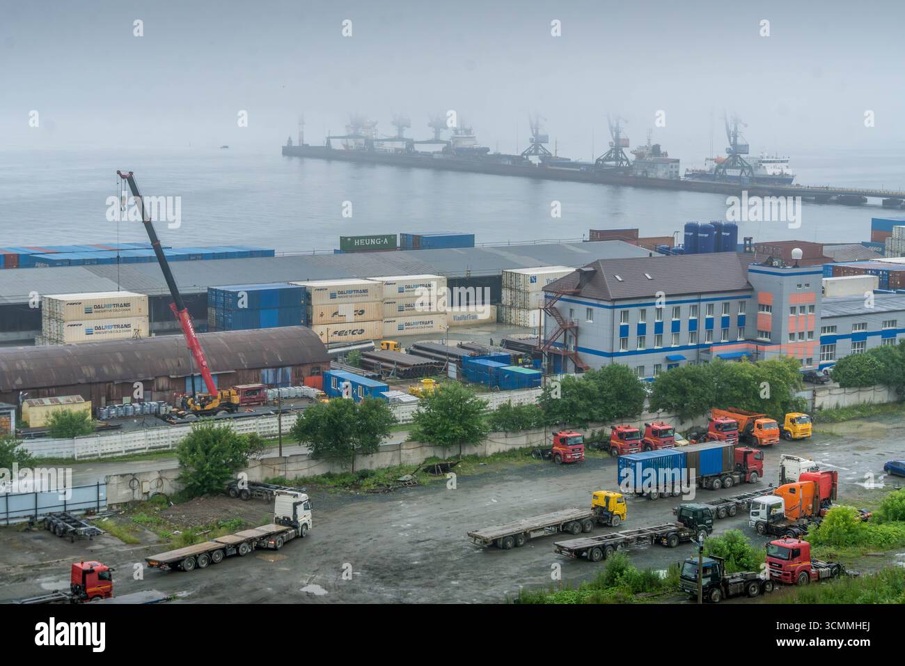 Panorama industriel du front de mer avec grues et navires, Korsakov, Sakhaline, Russie, avec entrepôts portuaires, matériaux de construction, rue humide Banque D'Images