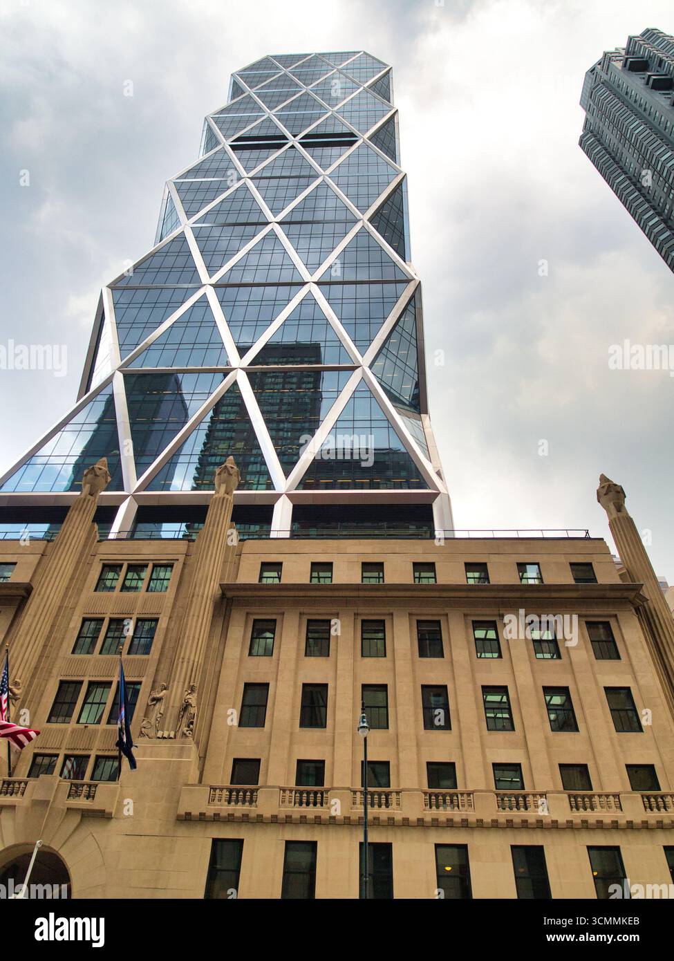 Hearst Tower à New York - Une vue en bas angle de la Hearst Tower moderne en verre à facettes s'élevant au-dessus de sa base historique classique par une journée nuageuse Banque D'Images