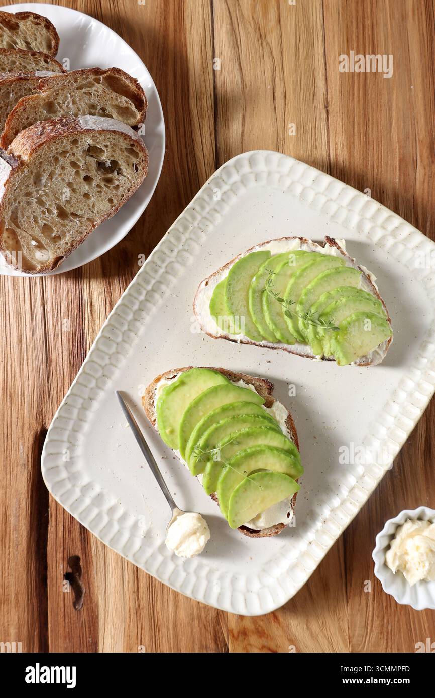 Vue de dessus pain Sourdough avec tranche d'avocat, pain grillé AVO et pâte à tartiner au fromage à la crème, sur table en bois Banque D'Images