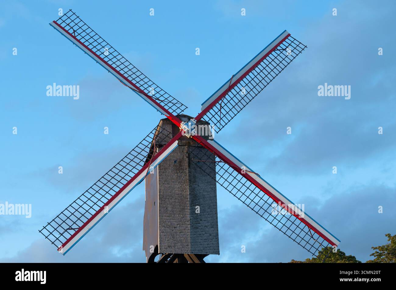 Un moulin à vent captivant et pittoresque aux superbes pales rouges tourne gracieusement sous un ciel bleu clair Banque D'Images
