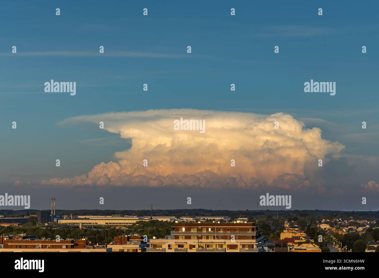 Un superbe paysage urbain capturé à l'aube, avec une spectaculaire formation de nuages dorés illuminée par le soleil levant. L'image met en valeur une ville dynamique Banque D'Images