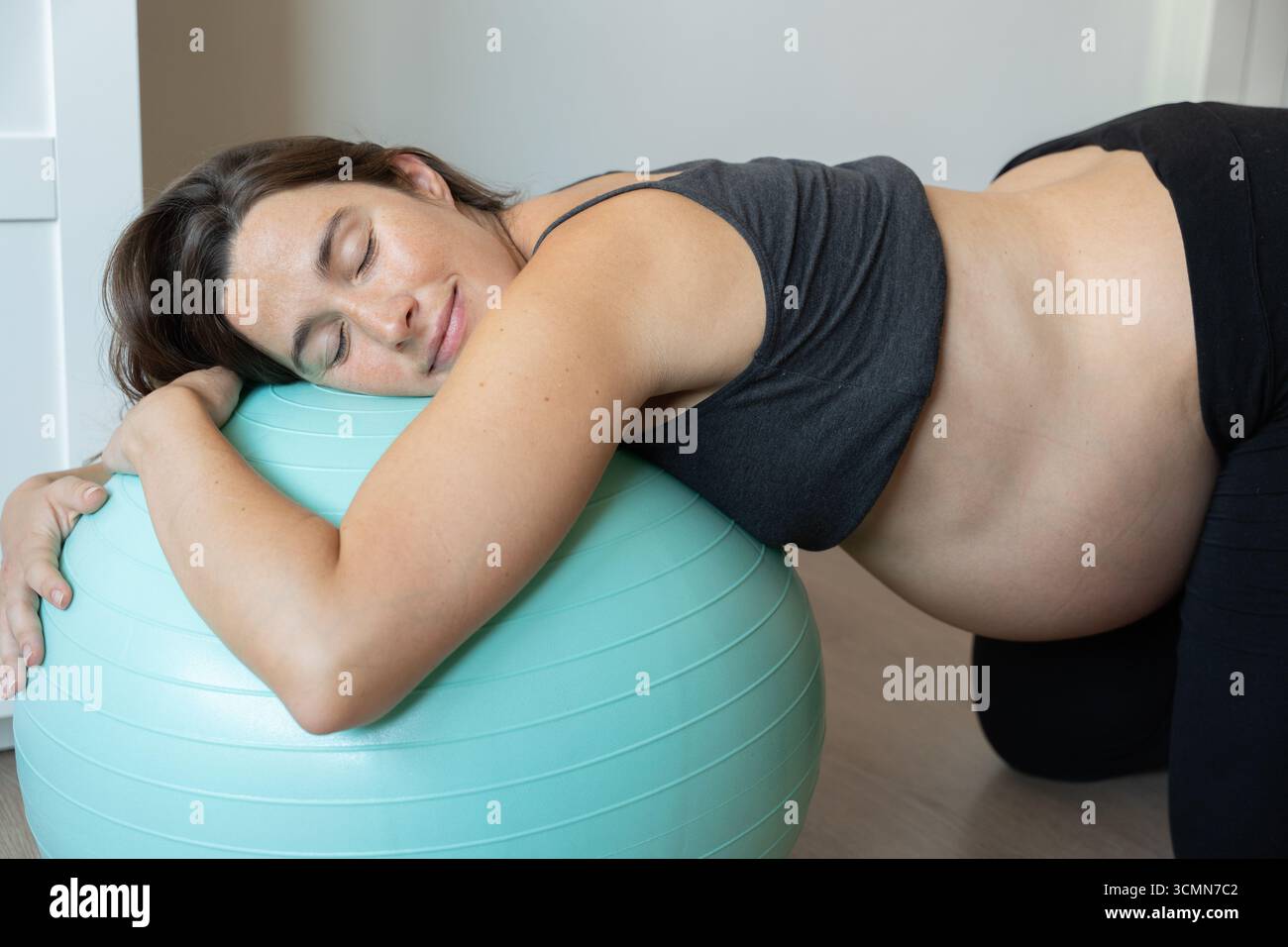 Femme enceinte se relaxant sur le ballon de fitness : embrasser le confort et le bien-être pendant la grossesse Banque D'Images
