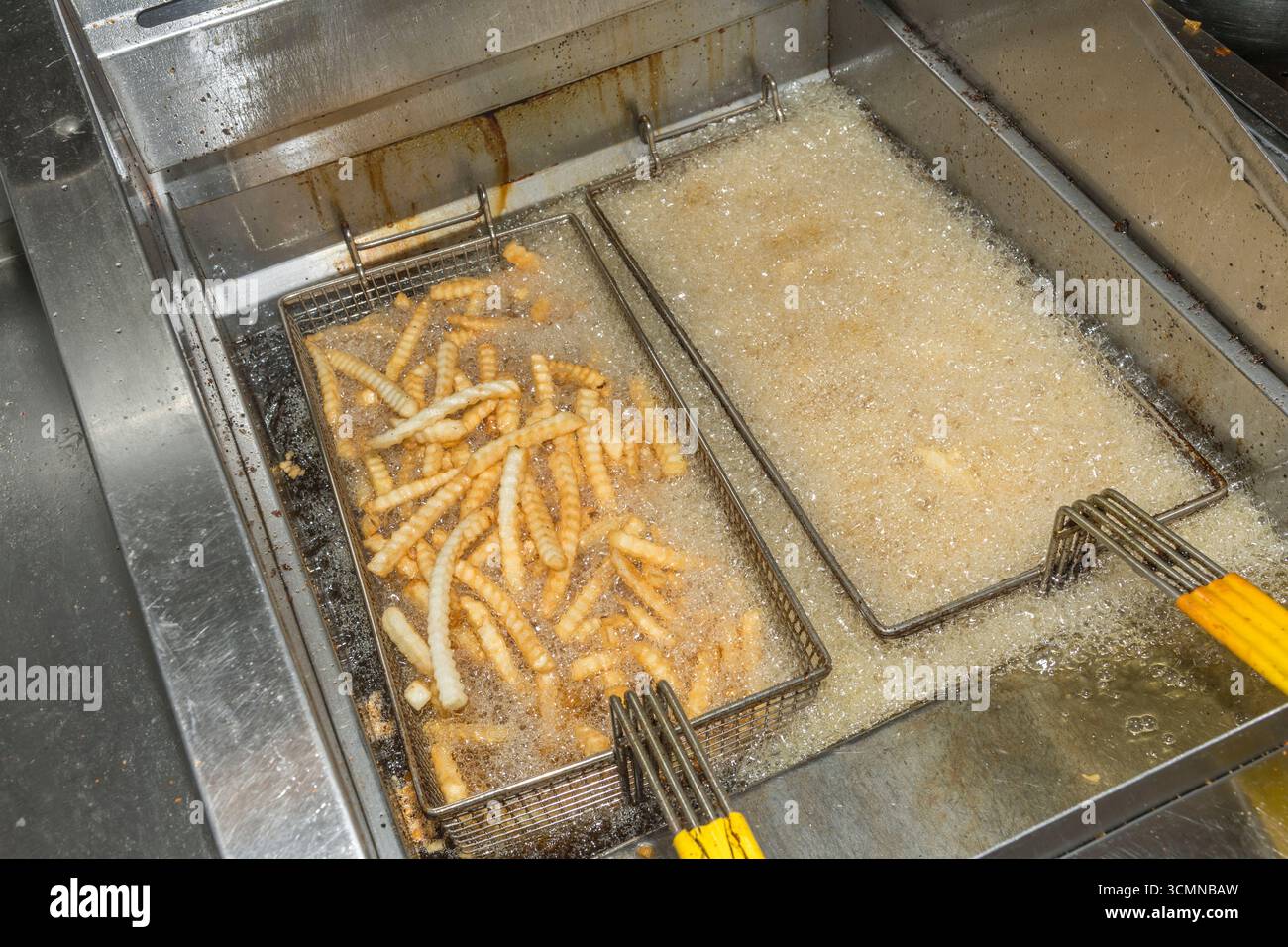 Frites cuites dans des paniers dans une friteuse dans la cuisine de restauration rapide de restaurant commercial, États-Unis Banque D'Images