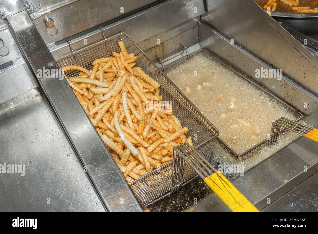 Frites cuites dans des paniers dans une friteuse dans la cuisine de restauration rapide de restaurant commercial, États-Unis Banque D'Images