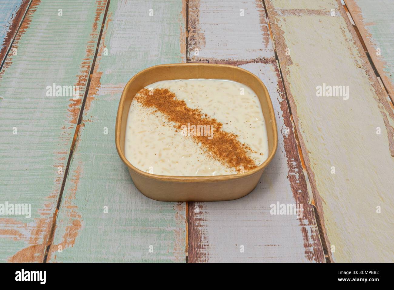 Pudding de riz moderne à base de flocons d'avoine et de lait d'amande, garni de compote de pommes et de noix caramélisées pour un contraste de texture. Banque D'Images