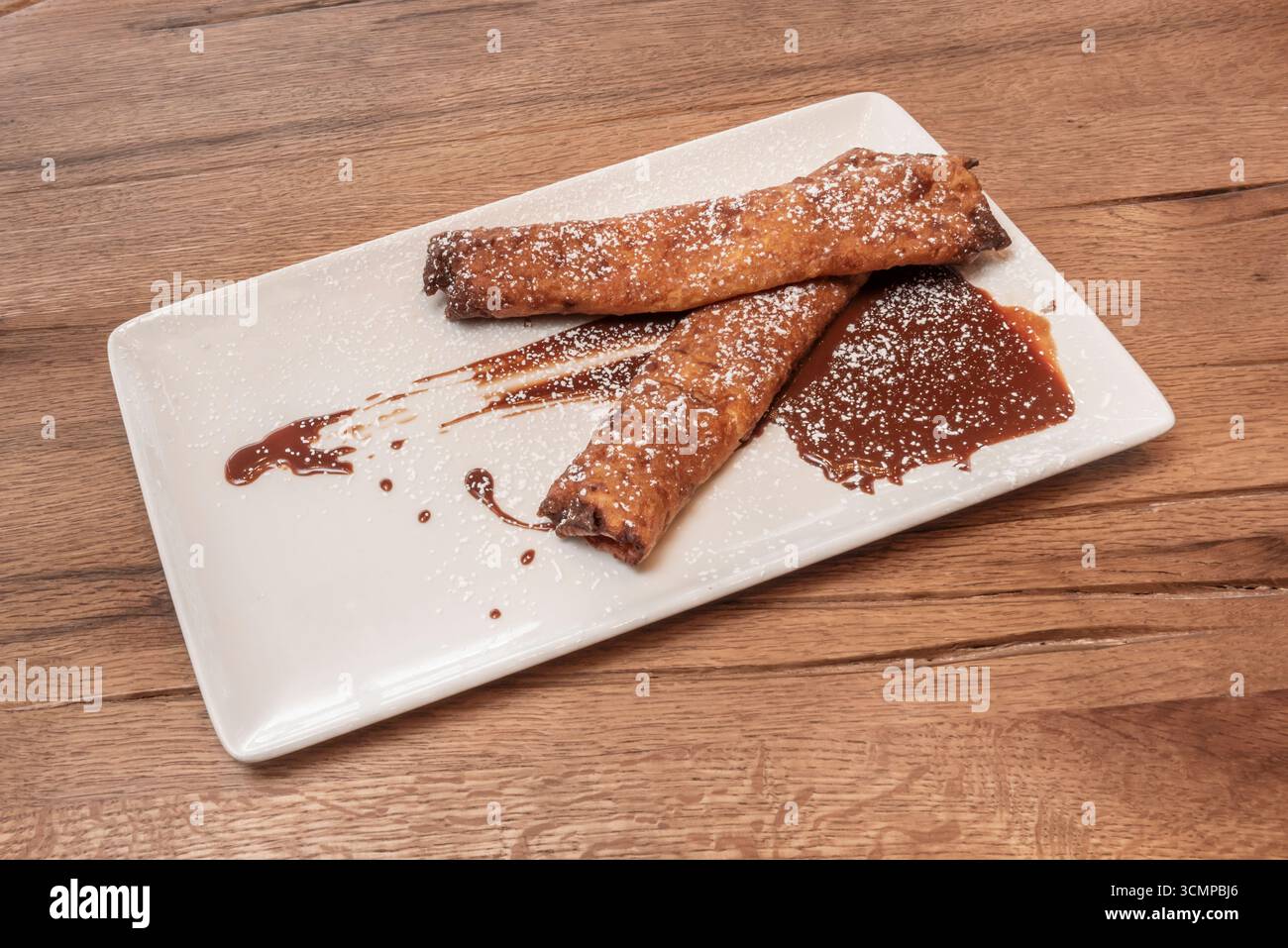 Crêpes moelleuses au chocolat fourrées de praliné aux noisettes et de morceaux de brownie, accompagnées d'une sauce au caramel salé Banque D'Images