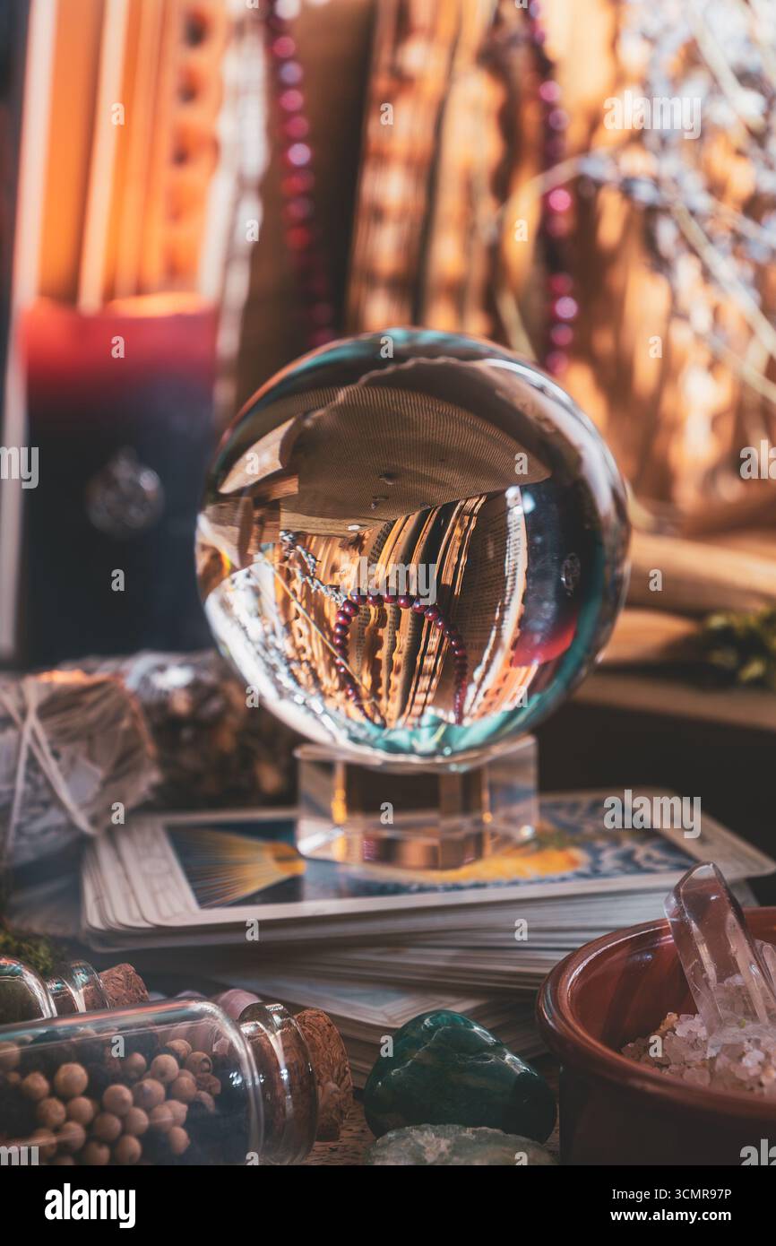 Boule de cristal mystique reposant sur des cartes de tarot entourées de pierres précieuses, d'herbes et d'outils d'autel magiques pour la divination et les rituels spirituels. Banque D'Images
