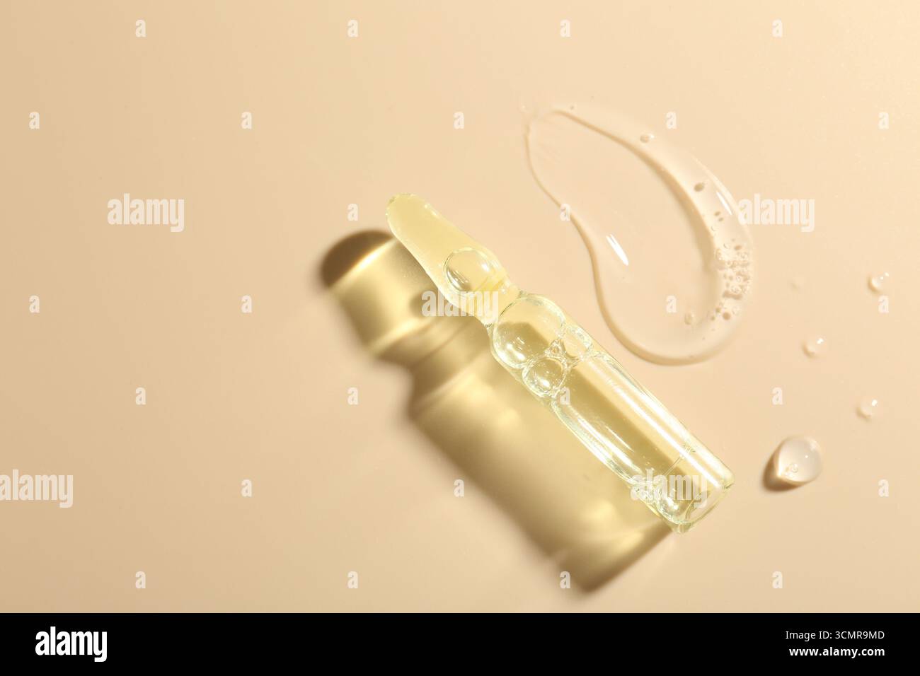 Ampoule en verre avec produit cosmétique et échantillon sur fond beige, vue de dessus. Espace pour le texte Banque D'Images