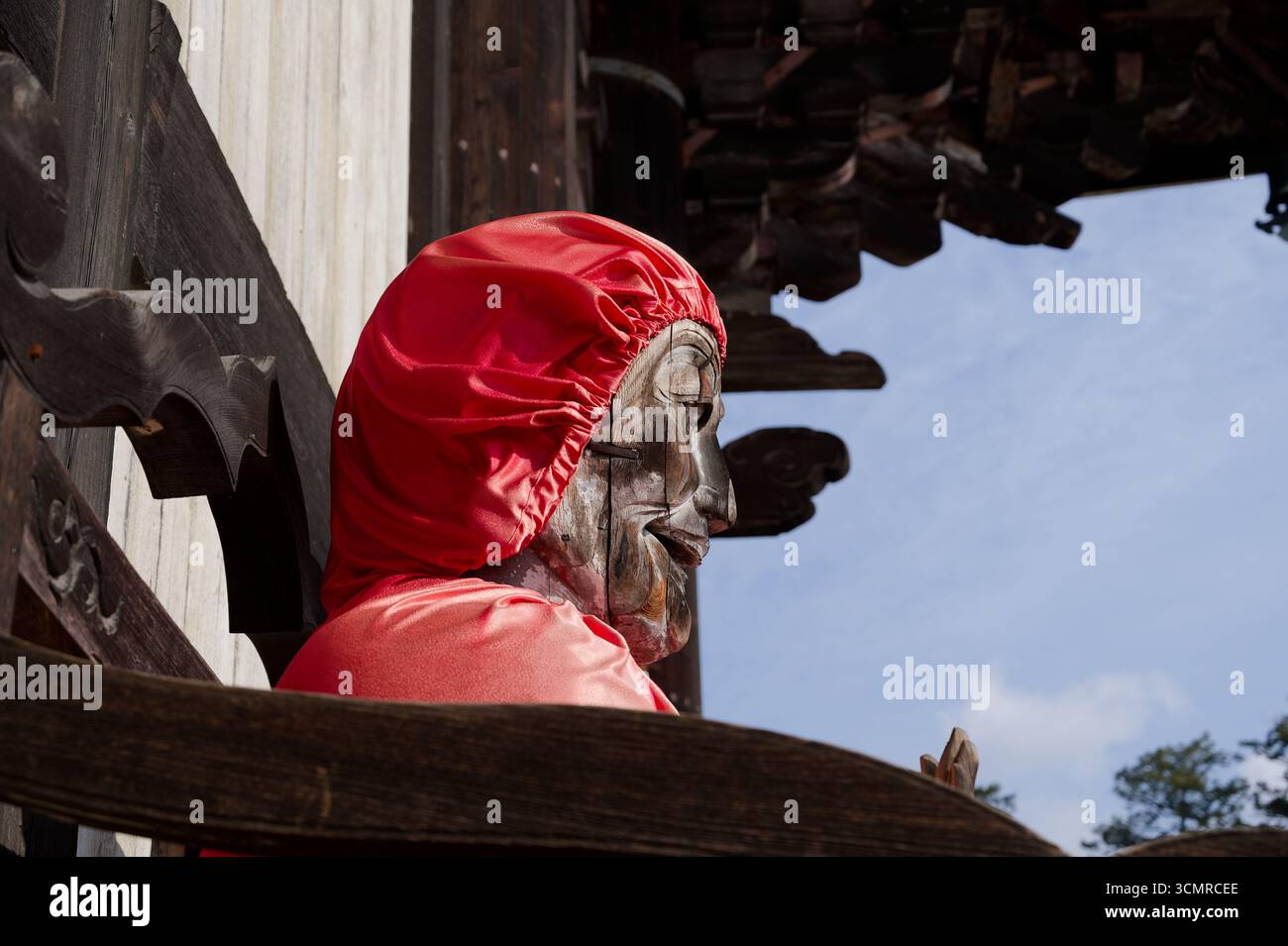 Statue en bois vieilli habillée d'un tissu rouge à l'extérieur du temple Todai-ji à Nara Banque D'Images
