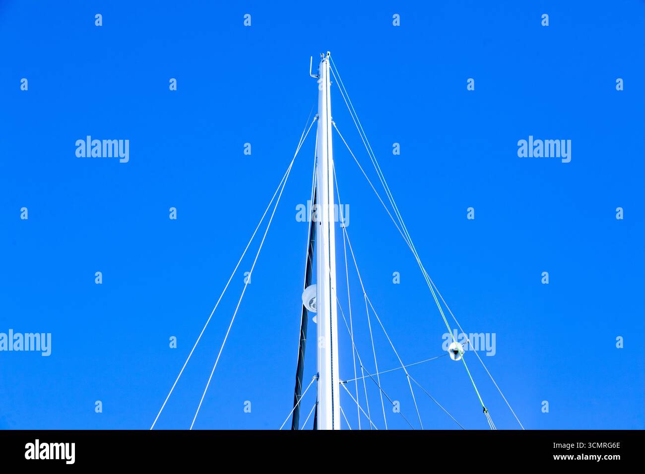 Le mât d'un yacht à voile avec un radar, des cordes à voile et une voile pliée, vu d'en bas contre le ciel. Banque D'Images