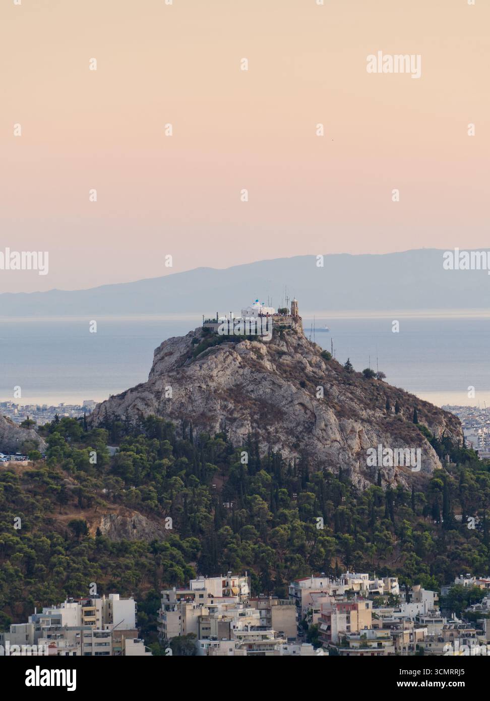 Vue aérienne de la colline de Lycabette avec chapelle au coucher du soleil à Athènes, Grèce avec étalement urbain ci-dessous Banque D'Images