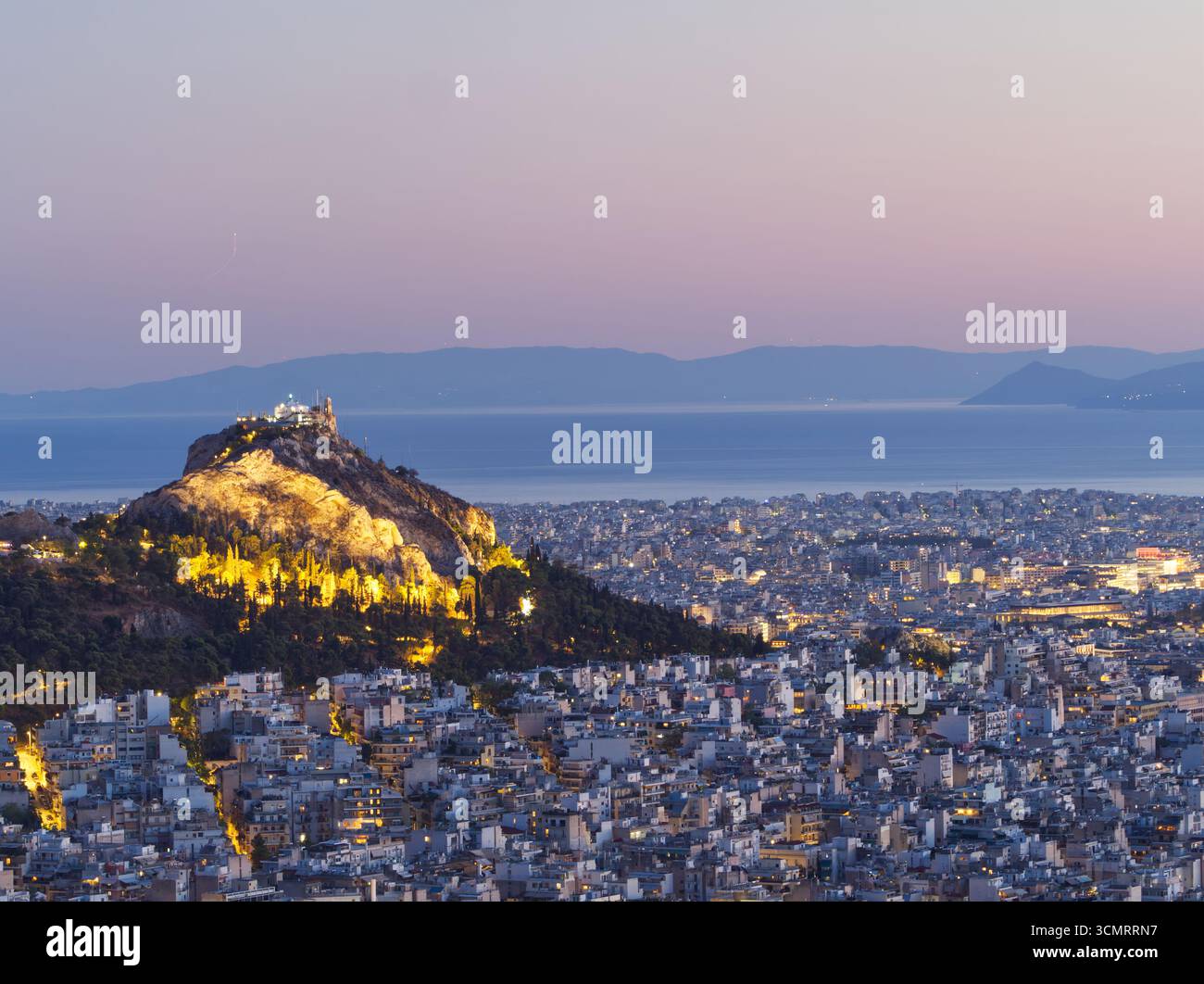 Vue panoramique de la ville d'Athènes avec la colline illuminée de Lycabette et les montagnes en arrière-plan au crépuscule Banque D'Images