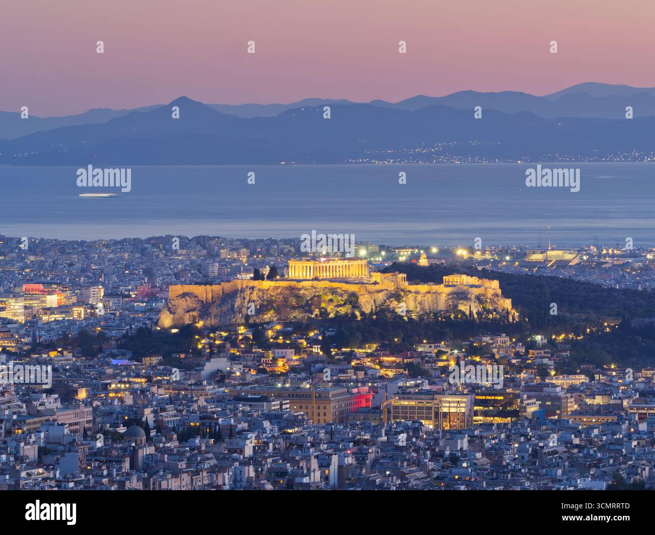 Acropole illuminé et Parthénon surplombant le paysage urbain d'Athènes au crépuscule avec les montagnes au-delà Banque D'Images