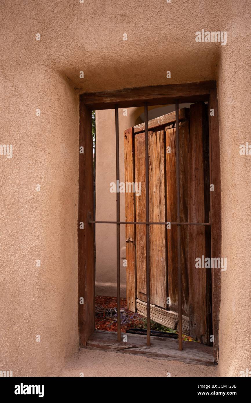 Grande porte en bois antique ouverte derrière une porte en fer ou une porte dans une maison adobe à Santa Fe, Nouveau-Mexique U.S.A. formes rectangulaires image verticale Banque D'Images