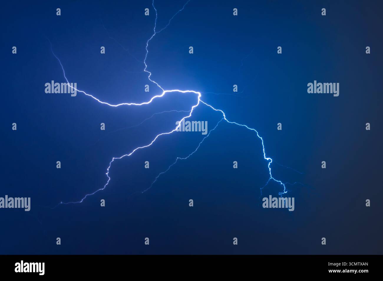 Foudre électrique puissant illuminant les nuages orageux contre le ciel nocturne bleu profond. Phénomène naturel spectaculaire capturé pendant l'orage avec Br Banque D'Images