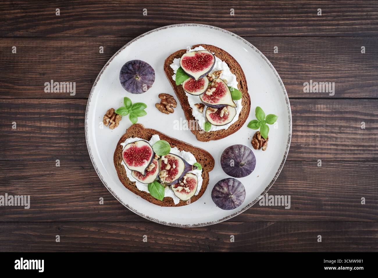 Sandwichs aux figues, fromage à la crème, basilic et miel sur fond de bois, vue de dessus Banque D'Images