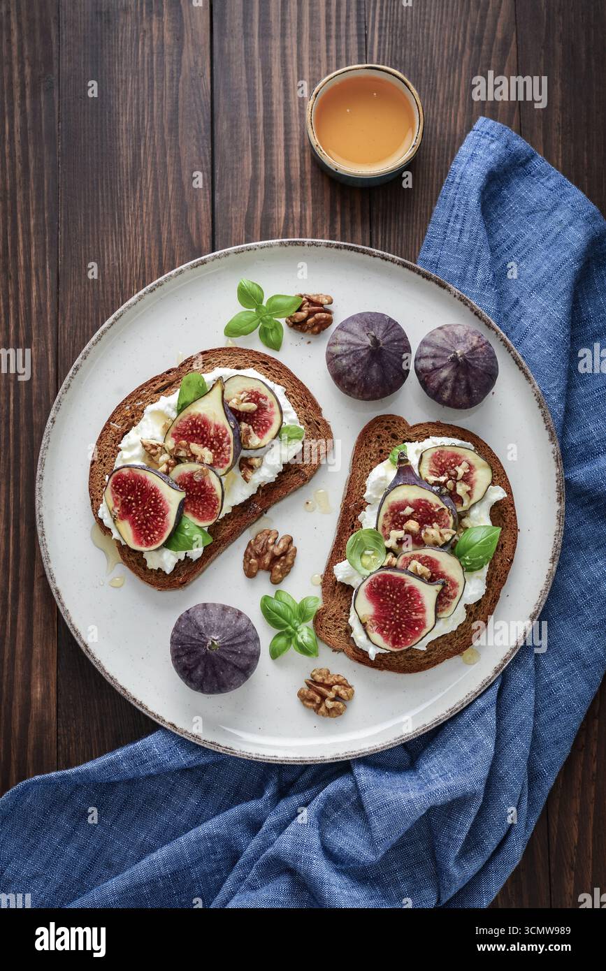 Sandwichs aux figues, fromage à la crème, basilic et miel sur fond de bois, vue de dessus Banque D'Images