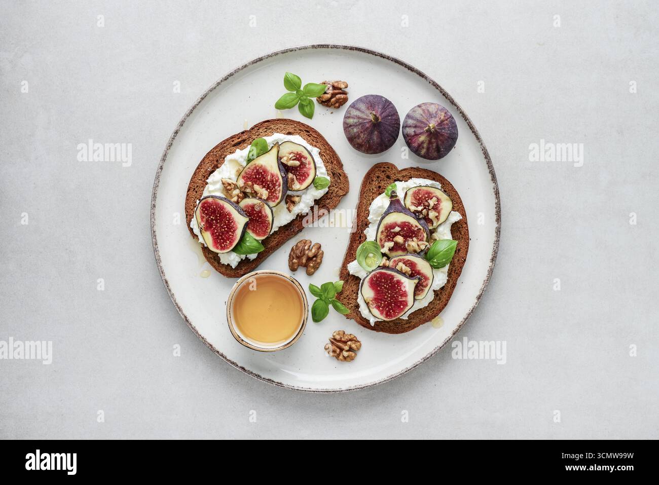 Sandwichs aux figues, fromage à la crème, basilic et miel sur fond clair, vue de dessus Banque D'Images