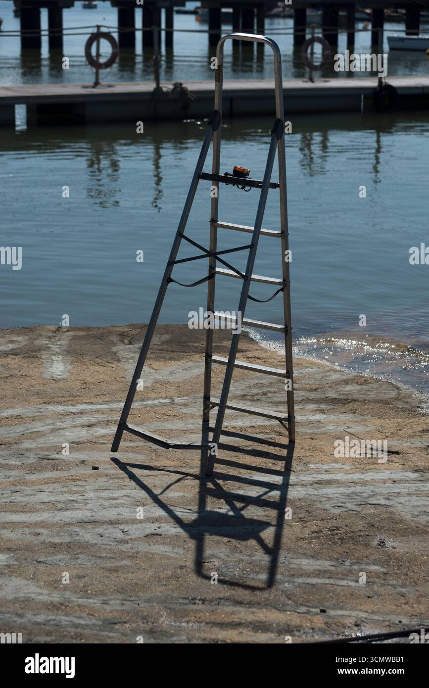 Escalera de mano abierta sita en la rampa de acceso al Agua en la zona de talleres del puerto del Rompido, en zona dembarque y desembarque de Barcos Banque D'Images