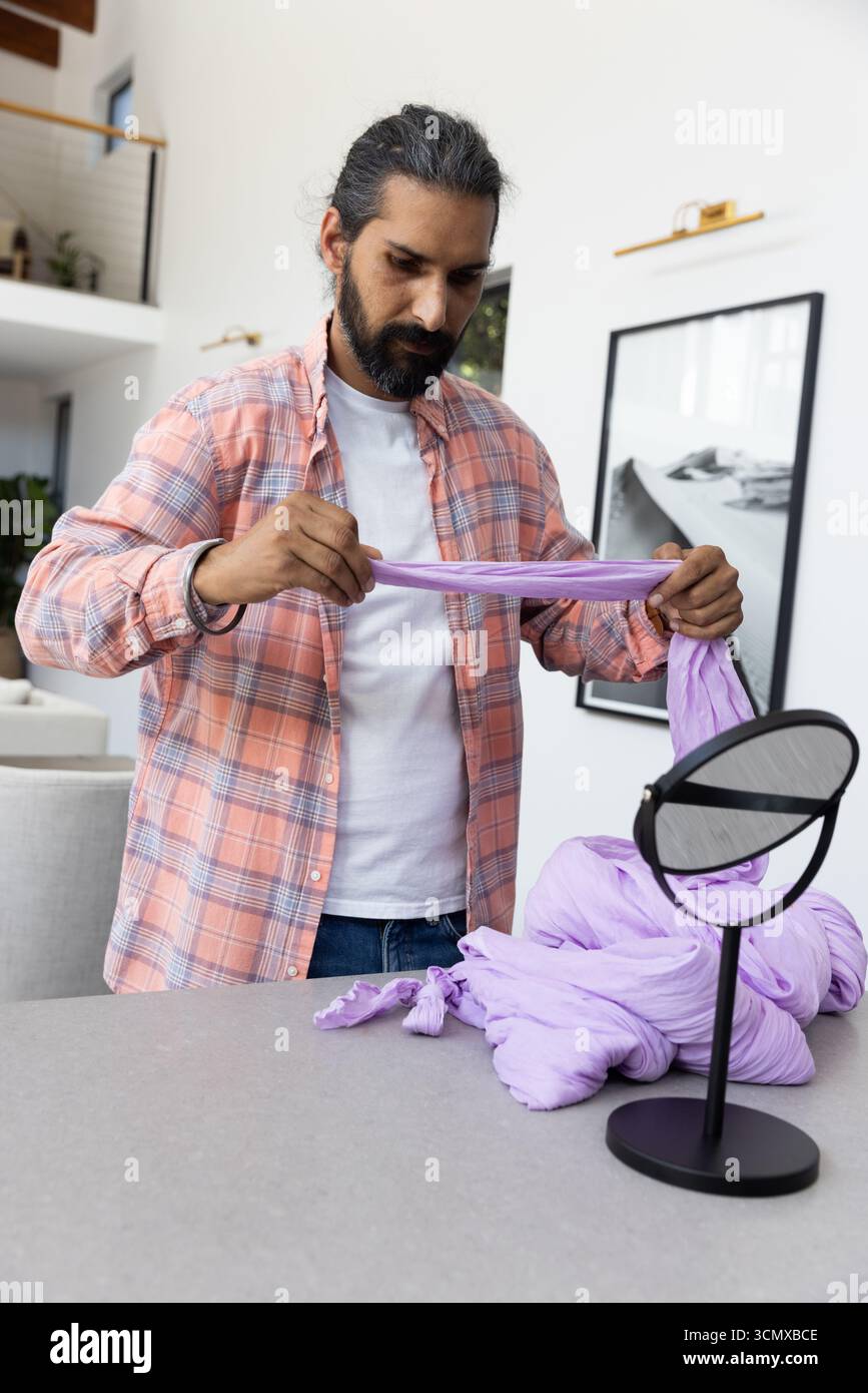 Homme indien tenant, étirant l'écharpe de lavande sur l'îlot de cuisine avec miroir de table Banque D'Images