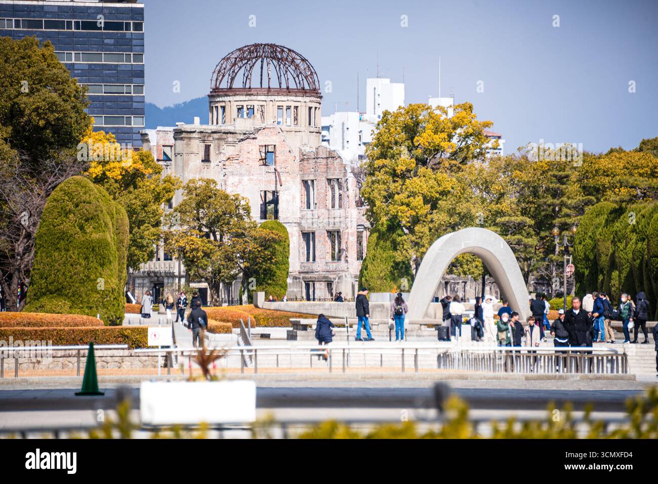 Vue du cénotaphe du mémorial de la paix d'Hiroshima et du dôme de la bombe atomique entourés de visiteurs dans le parc du mémorial de la paix, Hiroshima, Japon Banque D'Images