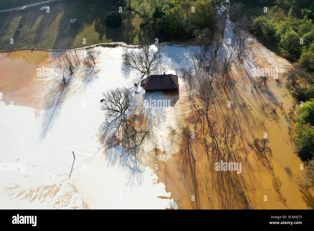 Vue aérienne de la maison de village en train de couler au milieu de l'étang de décantation de drainage de mine acide toxique. Geamana, Rosia Montana, Roumanie Banque D'Images