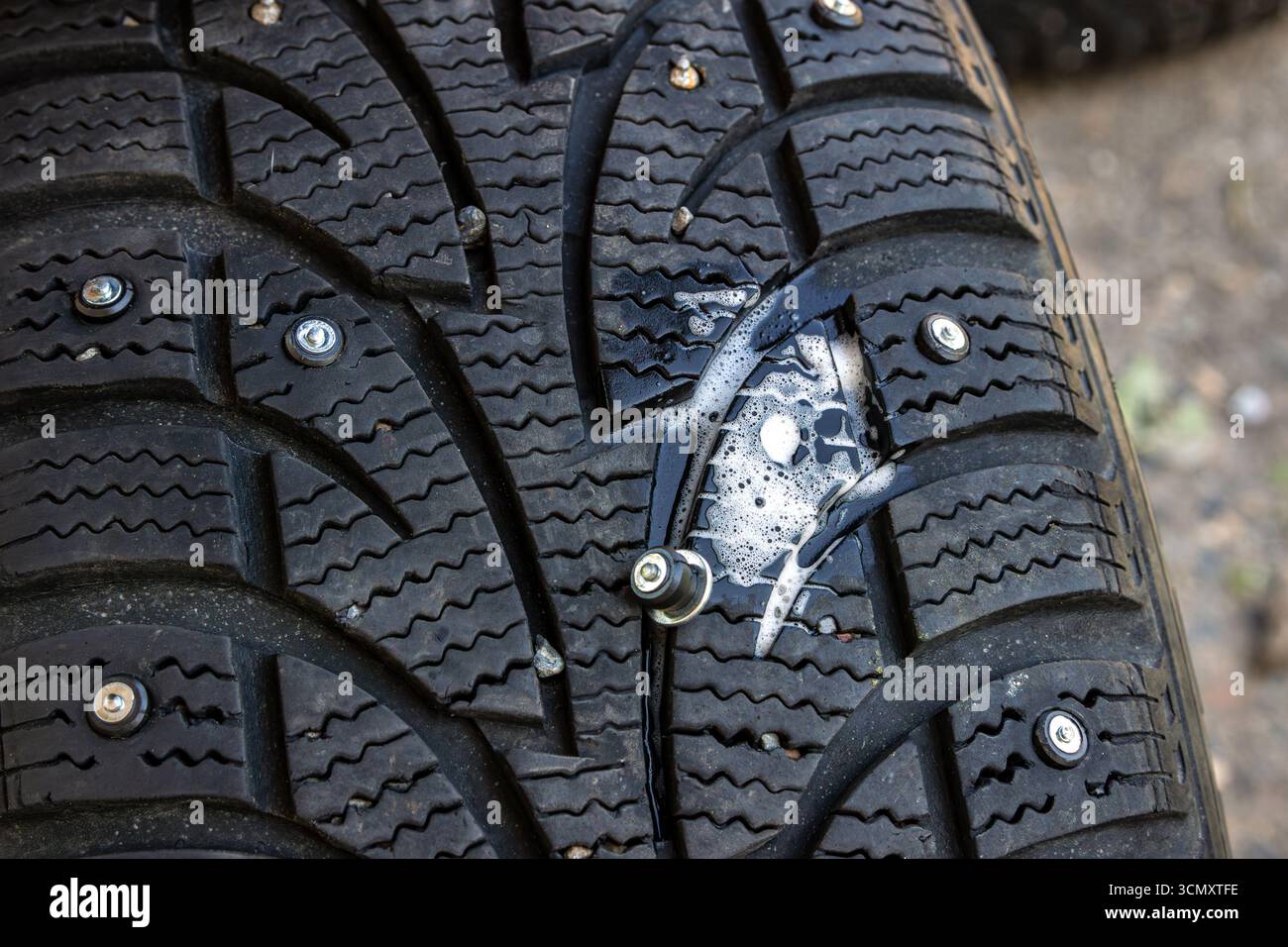 Gros plan d'un pneu d'hiver à clous montrant un trou vide rempli de lubrifiant savonneux pour réduire la friction et faciliter la pose correcte d'un pneu neuf Banque D'Images