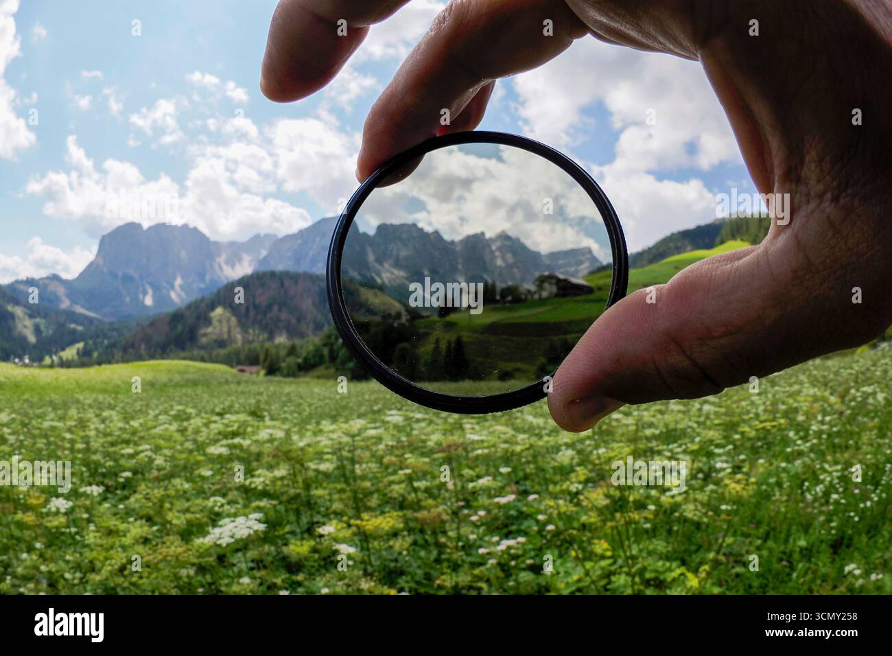 Filtre polarisant tenant la main montrant la différence de contraste du ciel dans le fond de montagne dolomites Banque D'Images