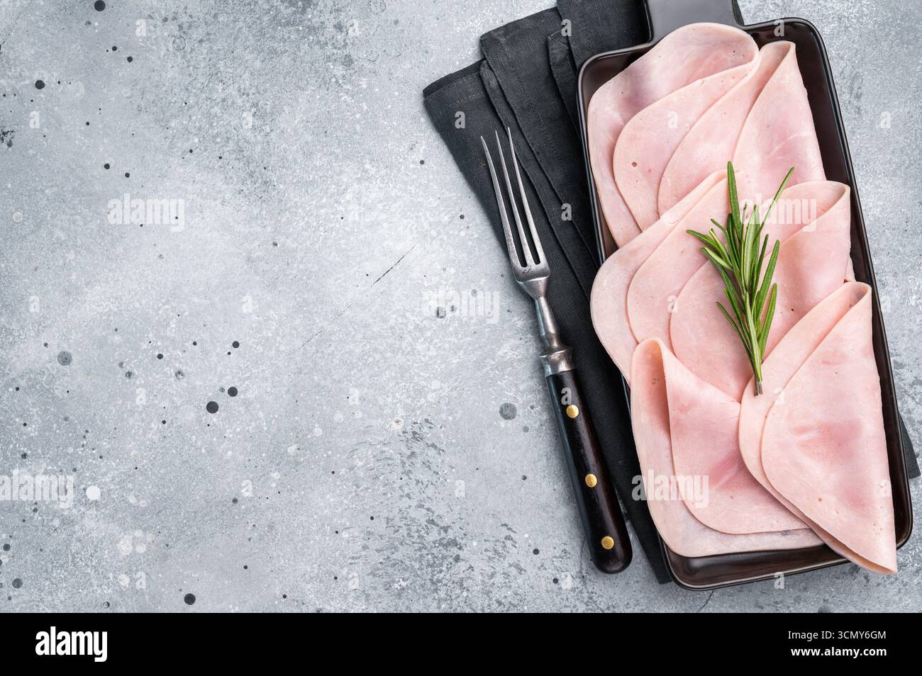 Jambon tranché gourmand sur une planche rustique, vous invitant à explorer de délicieuses recettes et de délicieuses associations. fond gris. vue de dessus. Banque D'Images