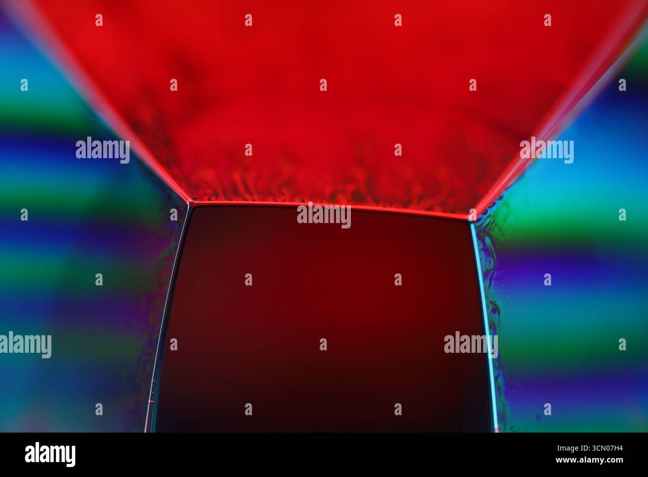 Macro Résumé du film de savon géométrique avec des motifs d'interférence rouge vif et arc-en-ciel irrégulier Banque D'Images
