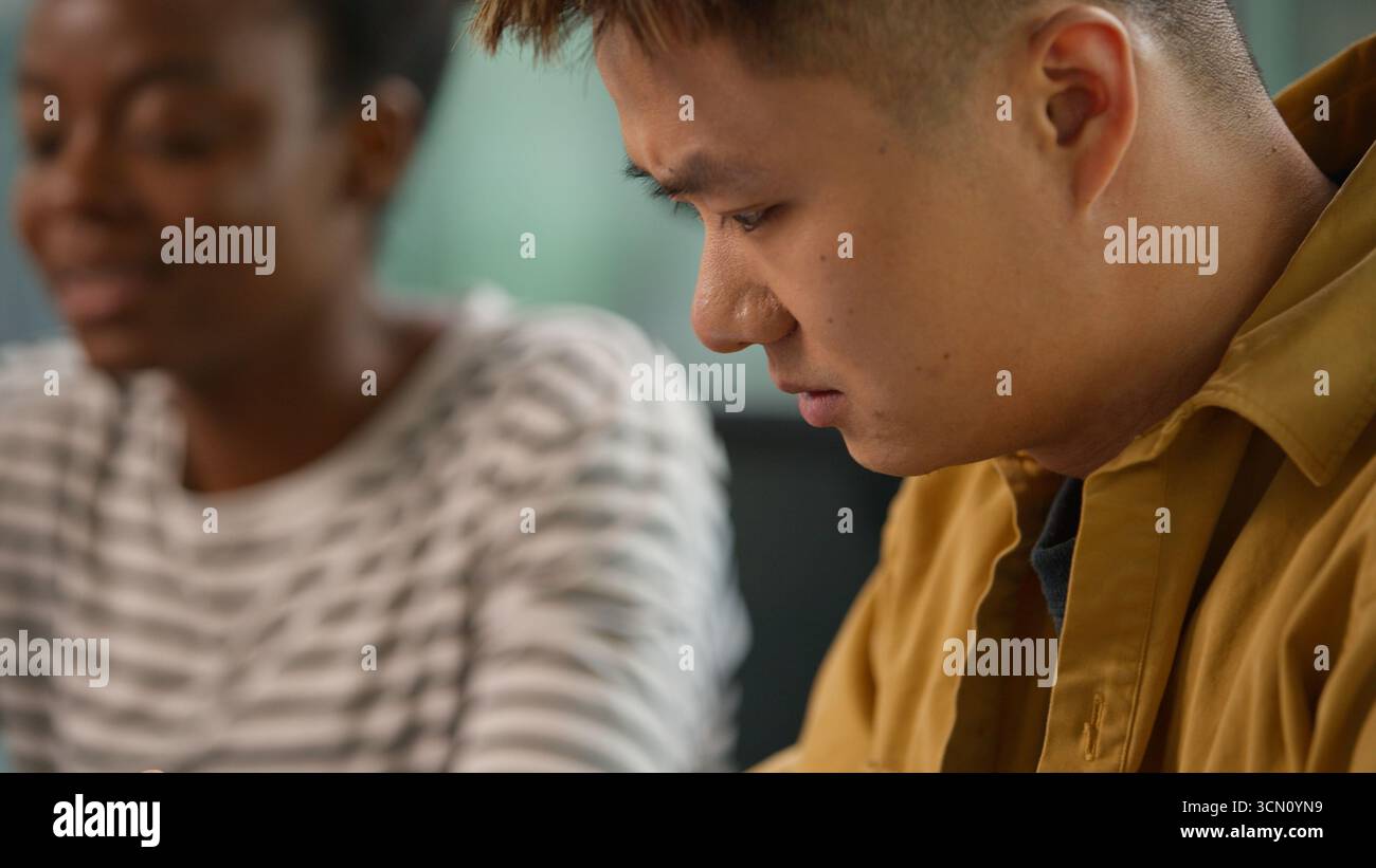 Homme d'affaires concentré asiatique homme d'affaires coréen à l'aide de gadget de tablette numérique navigation en ligne parlant sérieusement avec afro-américain Banque D'Images