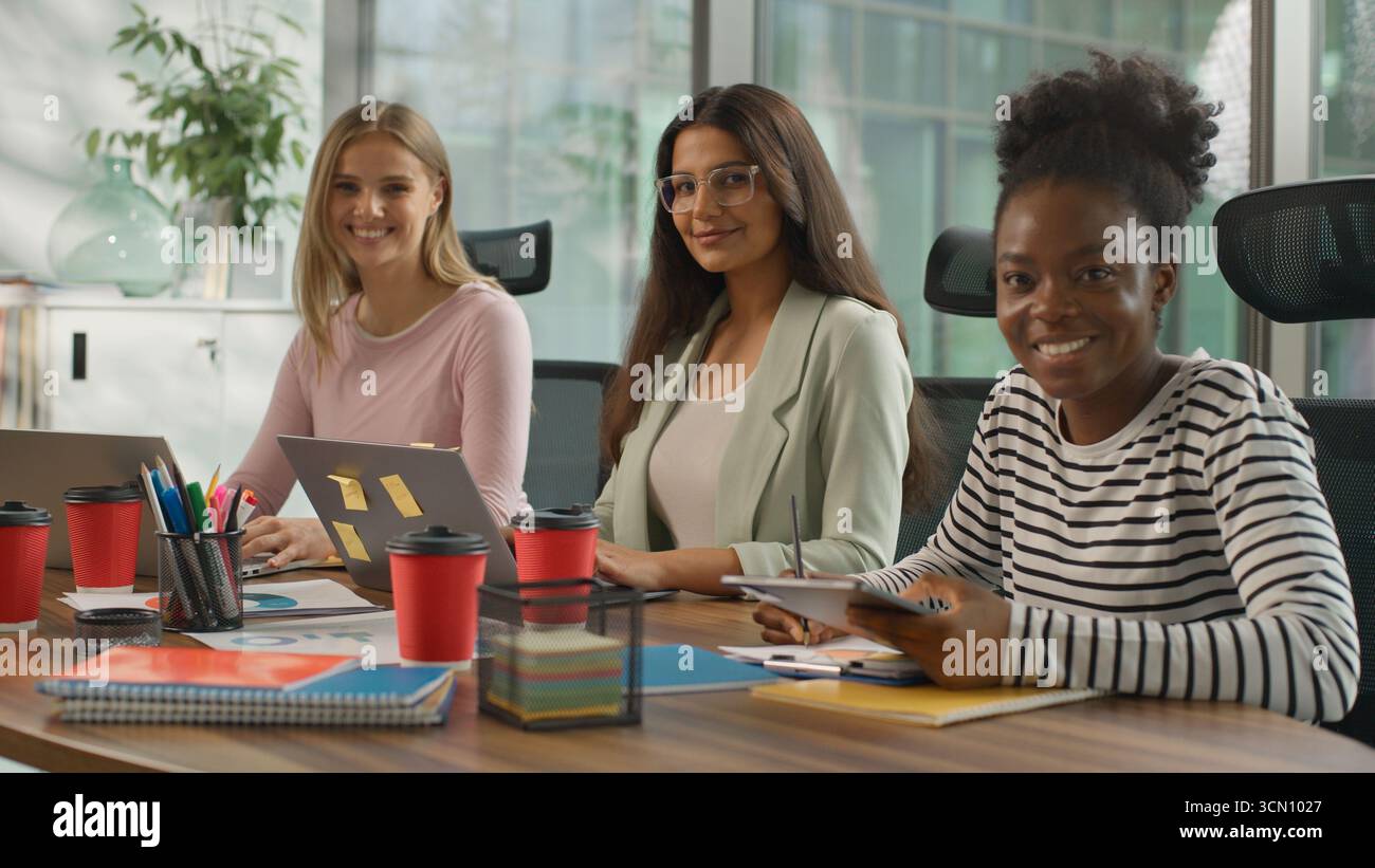 Trois femmes d'affaires informelles multiraciales travaillant dans le bureau des femmes d'affaires occasionnelles de diversité travaillent avec des ordinateurs portables écrivant des notes souriantes regardant Banque D'Images