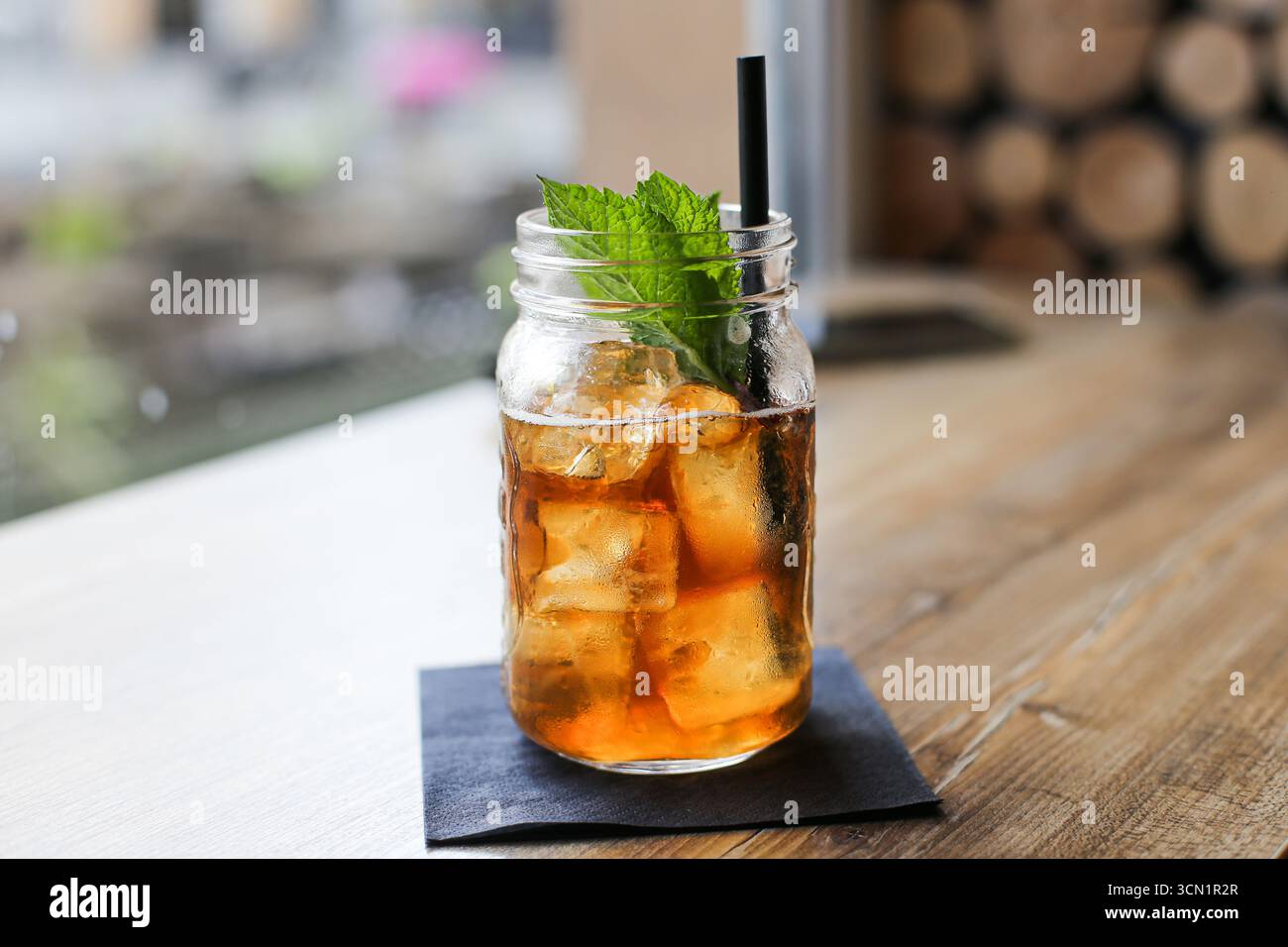 Thé glacé rafraîchissant avec des feuilles de menthe. Boisson froide dans un bocal en verre avec de la paille. Boisson d'été sur la table en bois. Concept de rafraîchissement sain en gros plan. Banque D'Images