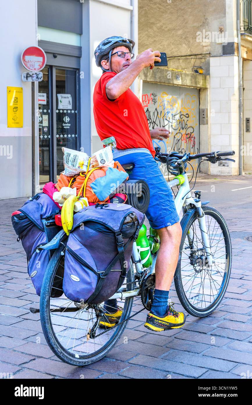 Touriste sur vélo lourdement chargé s'arrêtant pour prendre une photo avec smartphone dans le centre-ville - Tours, Indre-et-Loire (37), France. Banque D'Images