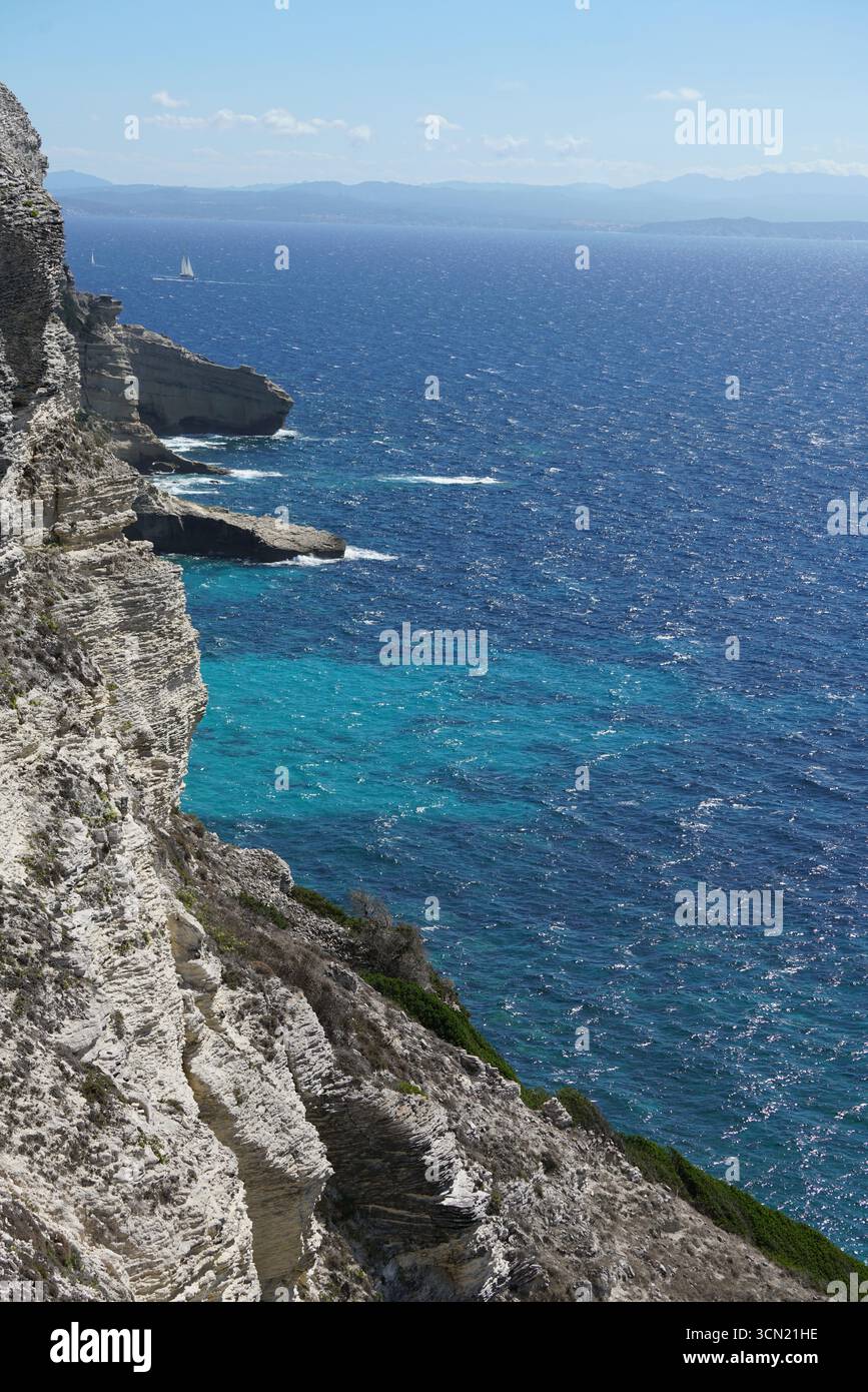 Cliffside Ocean View avec eau Turquoise, bateau à voile et horizon lointain. Bonifacio, Corse, France Banque D'Images
