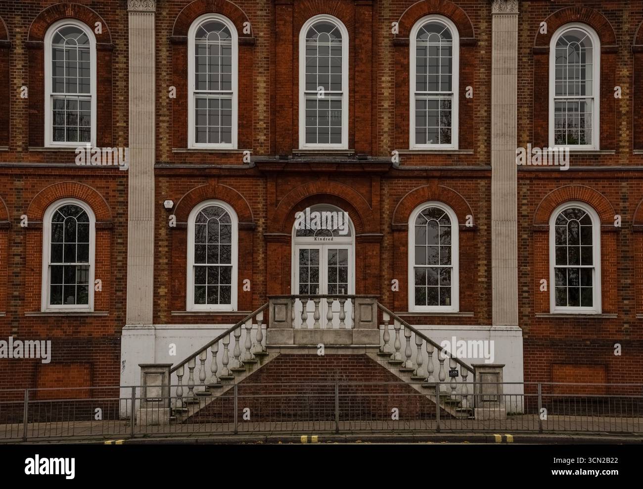 Façade de bâtiment historique en briques rouges avec fenêtres à guillotine cintrées et escalier en pierre, Hammersmith, Londres, Angleterre. Banque D'Images