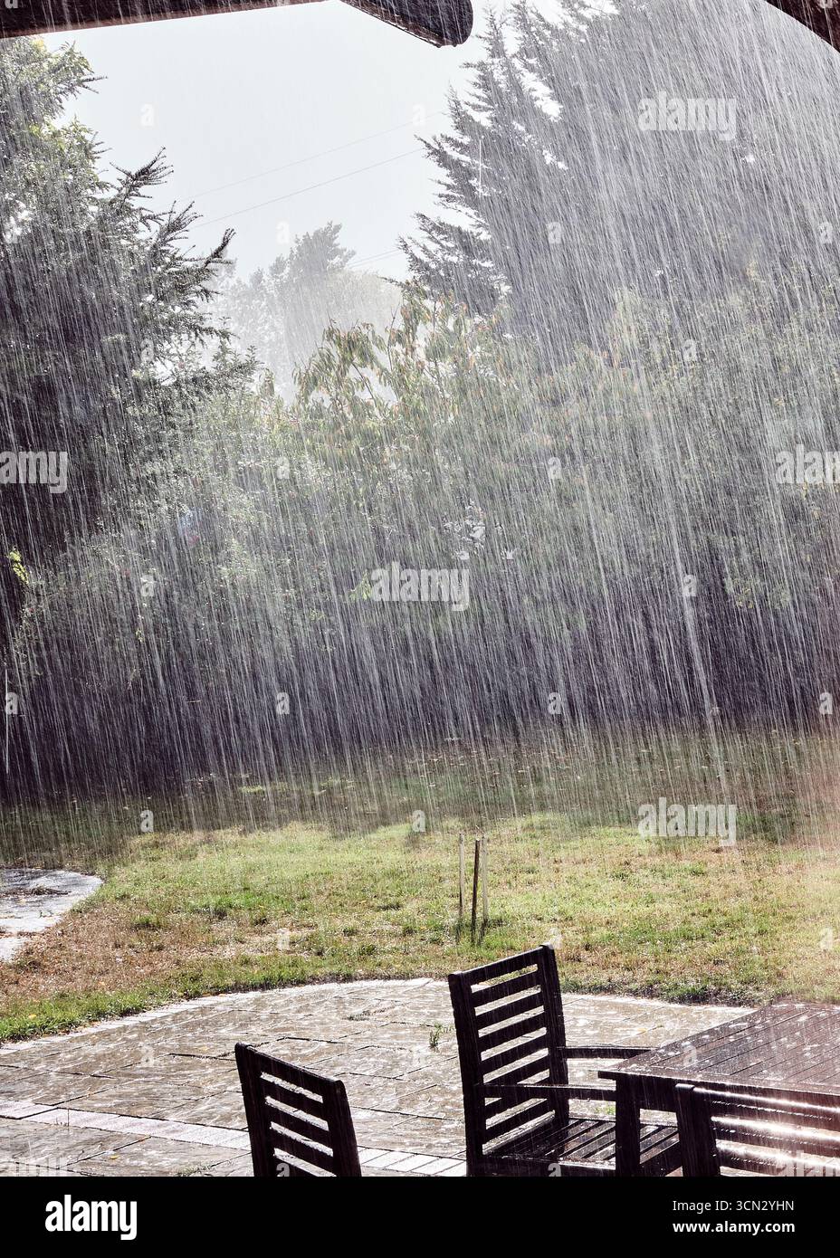 Stries de pluie sur le patio du jardin avec soleil en arrière-plan Banque D'Images
