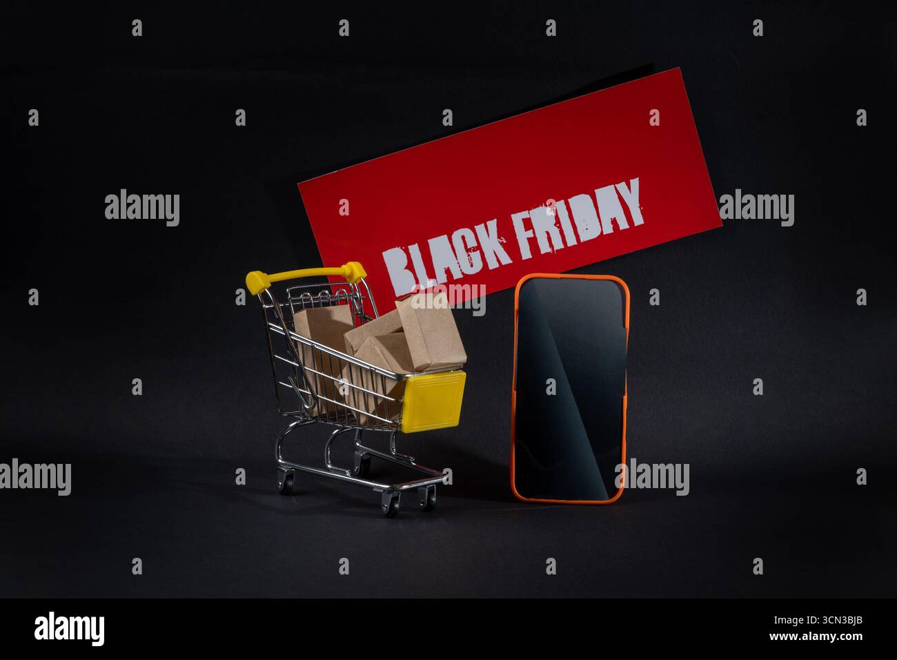 Chariot miniature plein de boîtes près d'un smartphone et panneau publicitaire Black friday, favorisant les achats et les ventes en ligne Banque D'Images