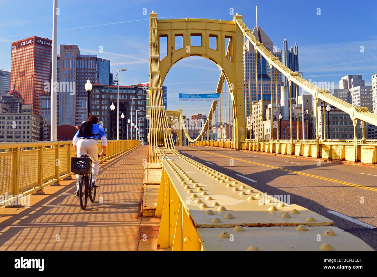 Un jeune homme adulte fait du vélo pour travailler sur le pont Roberto Clemente à Pittsburgh, en Pennsylvanie Banque D'Images