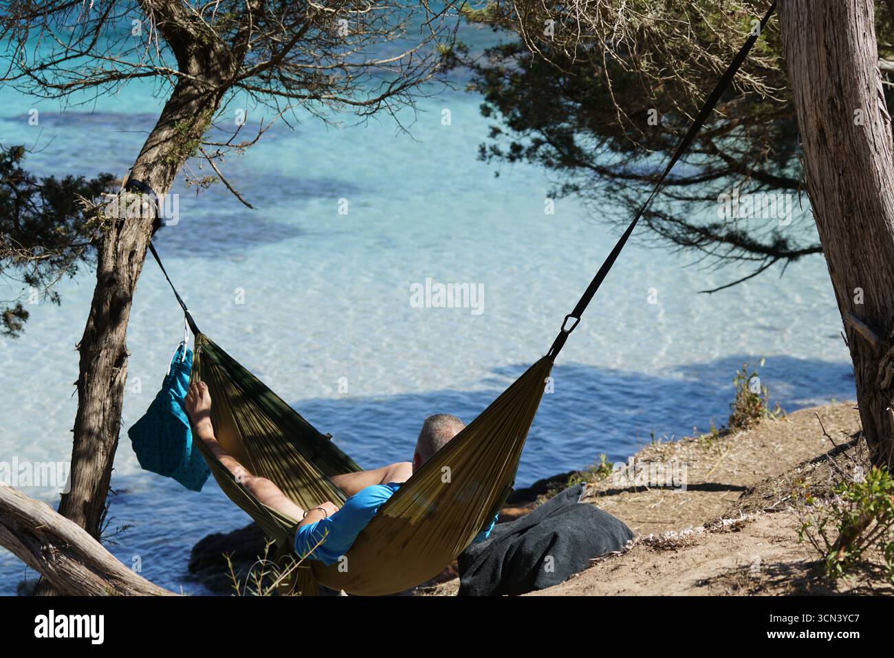 Hamac relaxant sur Crystal Blue Water près des arbres pour une escapade paisible en plein air. Plage de Santa Giulia, Corse, France Banque D'Images
