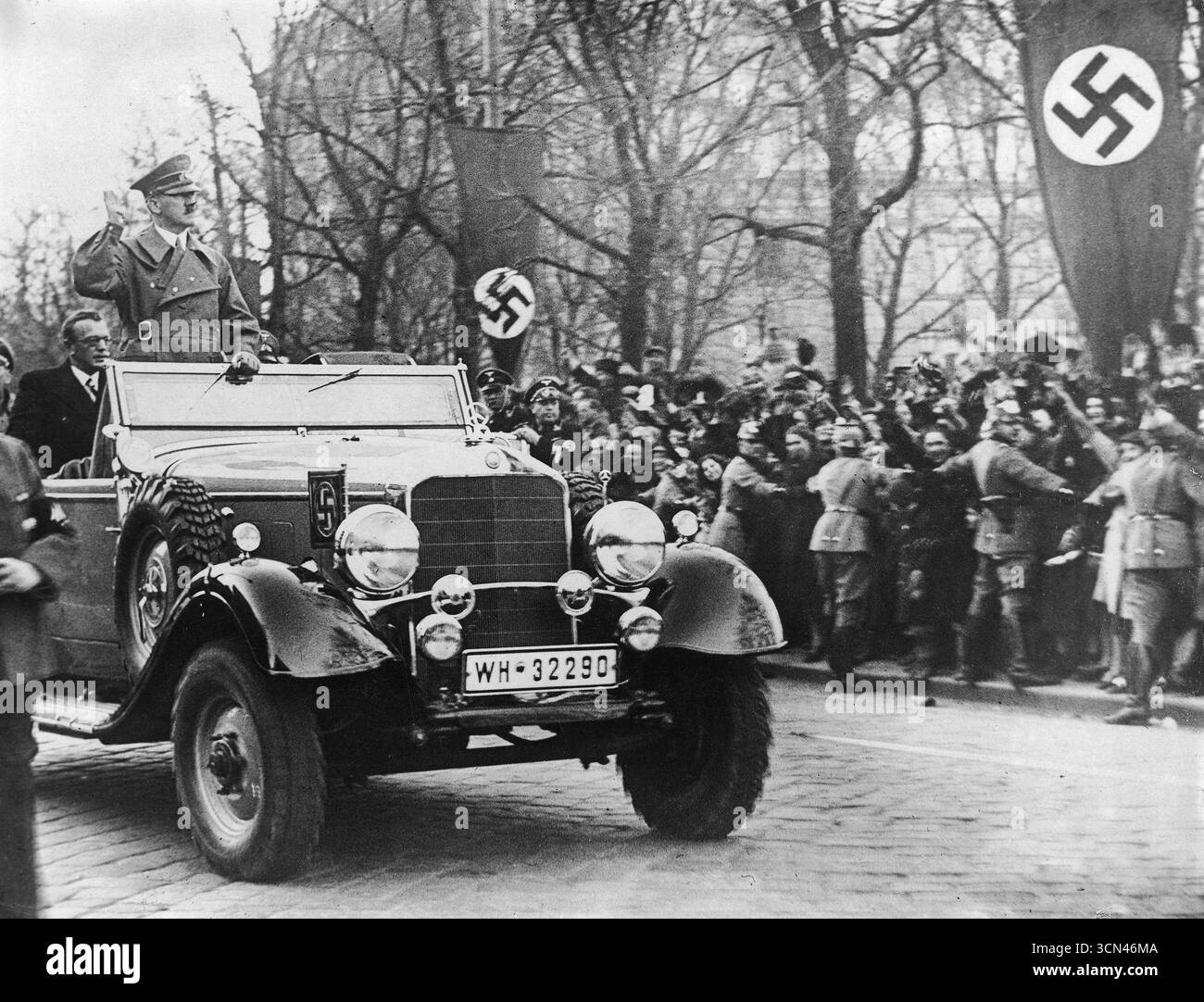 Adolf Hitler avec un salut nazi alors qu'il croise Sankt Pölten. Une foule massive sur les trottoirs. Autriche 1938 Banque D'Images