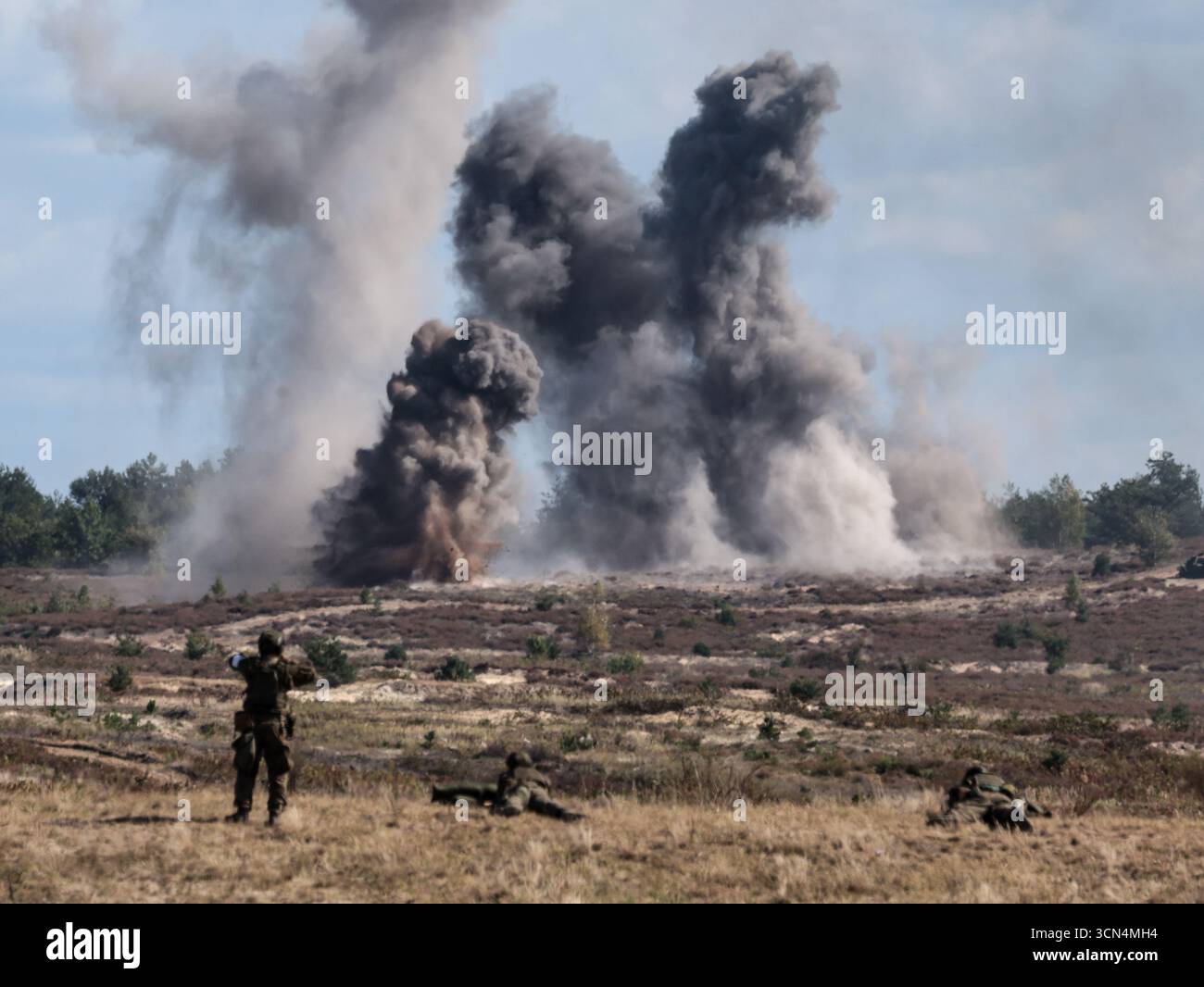 Explosions vues alors que des soldats d'infanterie polonais des Forces de défense territoriale s'entraînent à tirer à vue sous couvert lors de la journée médiatique Iron Defender 25. L’exercice Iron Defender 25 est l’événement d’entraînement le plus important et le plus important planifié par et pour les forces armées polonaises. Il s'agit d'une série d'exercices défensifs menés sur terre, dans les airs et sur l'eau par les forces terrestres, aériennes, navales, spéciales et territoriales de défense. Trente mille soldats et 600 pièces d'équipement des forces armées polonaises et des alliés de l'OTAN y participent. Banque D'Images