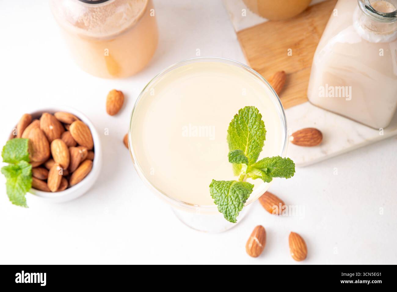 Cocktail d'orgeat au citron aigre-doux, recette de limonade à l'orgeat, un verre à martini avec boisson alcoolisée et bouteille de sirop d'orgeat d'amande Banque D'Images