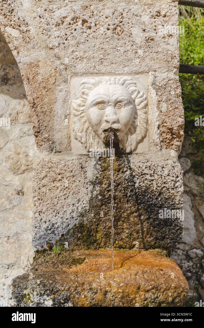 Vue d'une fontaine en pierre avec une tête de lion qui jaillit de l'eau dans un bassin mousseux à Frattura Vecchia, Abruzzes, Italie. Banque D'Images